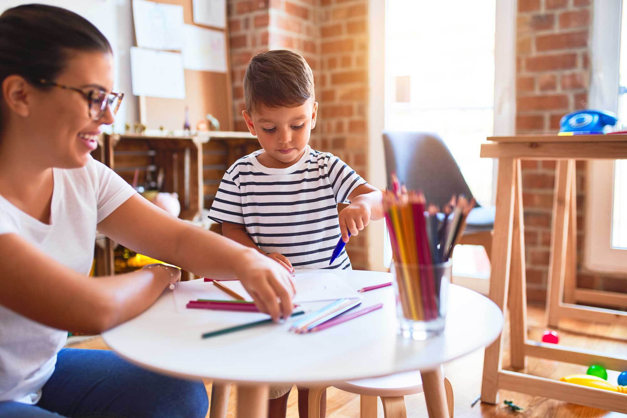 Teacher and young child coloring together