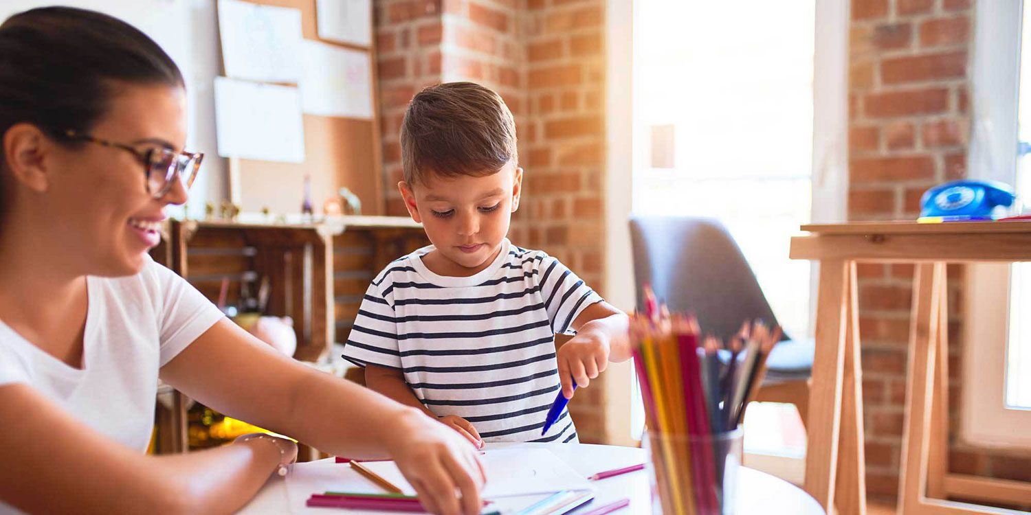 Teacher and young child coloring together